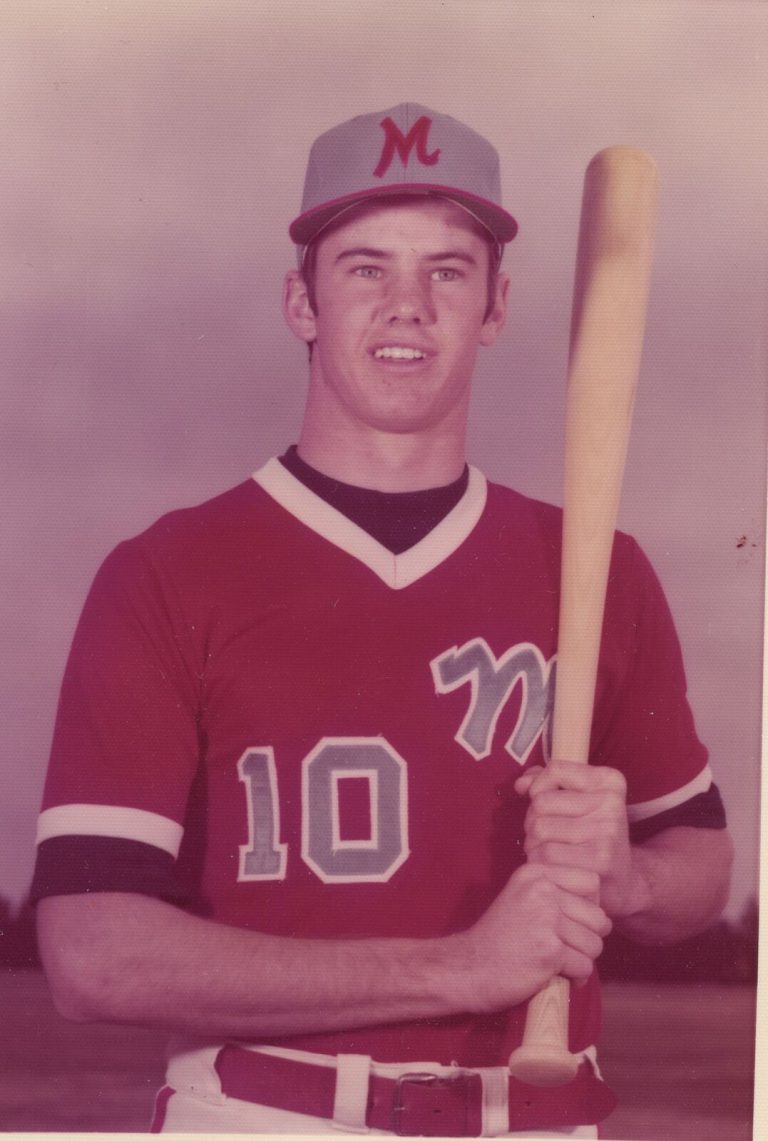 Tim Leslie in a red number 10 Monterey baseball jersey and cap, holding a bat, color portrait