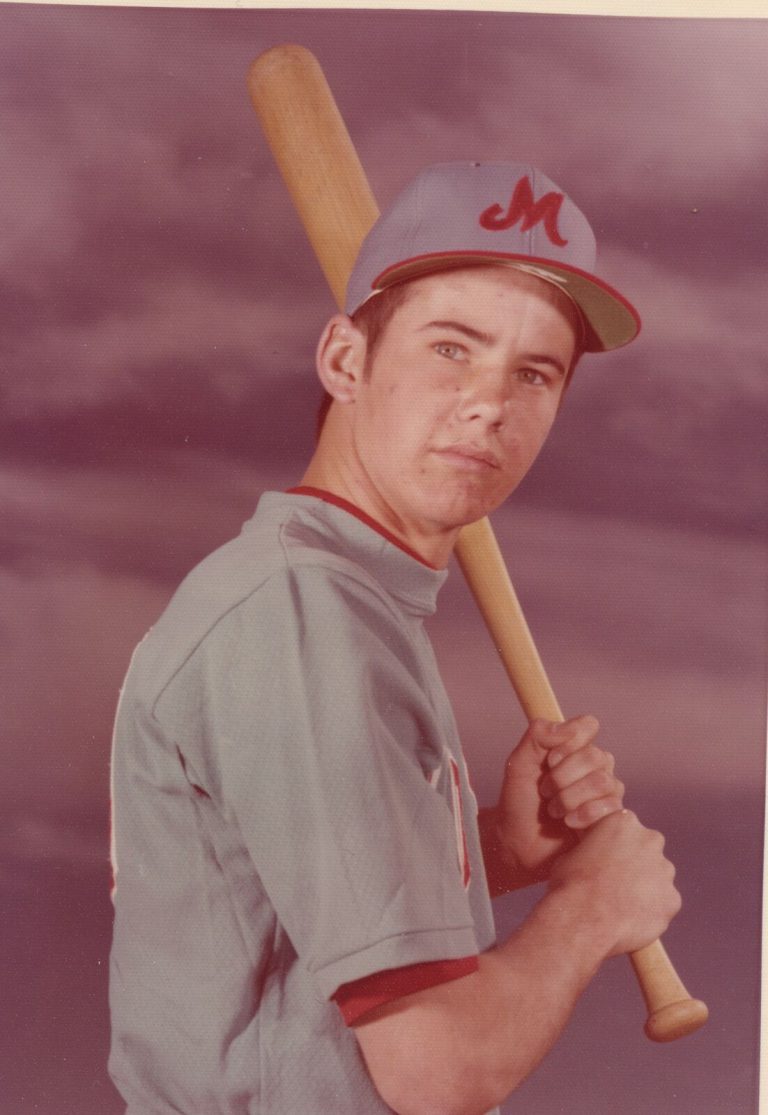 Tim Leslie in a Monterey baseball cap and gray jersey with a bat on the shoulder, color portrait