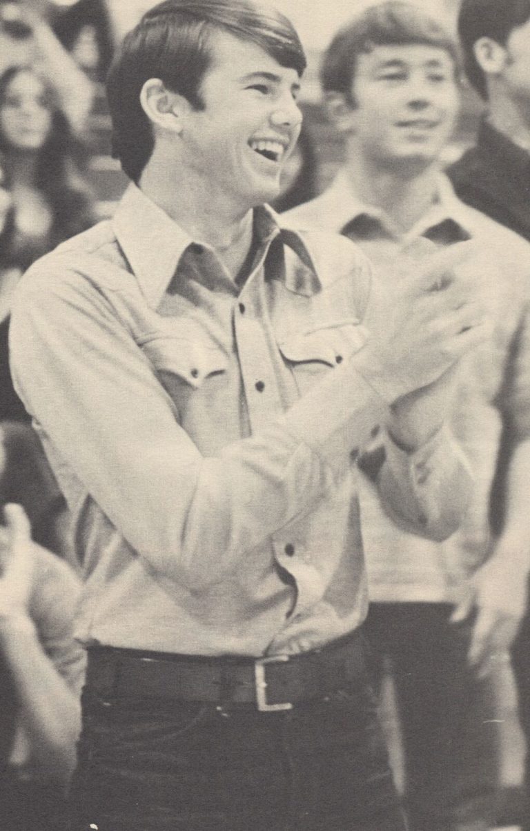 Tim Leslie laughing and clapping in a western-style shirt in a crowd, from a yearbook